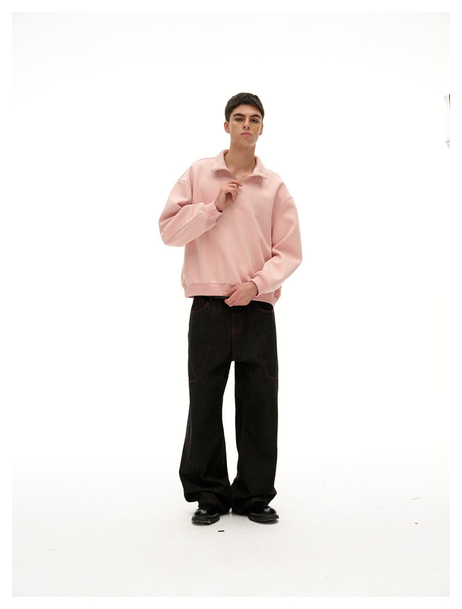 Full-length front view of a model wearing a pale pink quarter-zip pullover and loose black jeans.