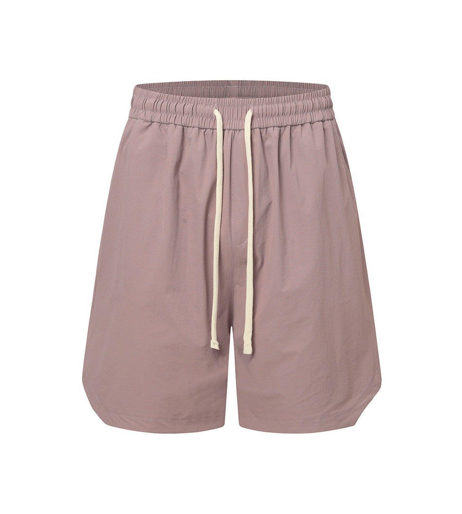 Dusty pink drawstring shorts with elastic waistband and curved side hems, front view on white background