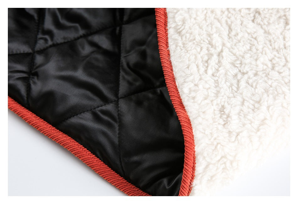 Close-up showing black quilted lining beside cream textured fabric, finished with coral-red binding.