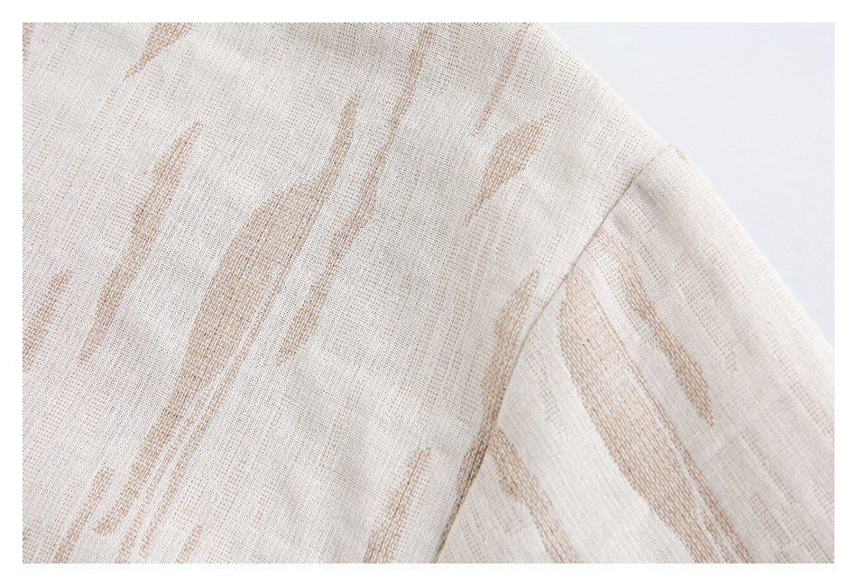 Close-up of the shoulder and sleeve seam on a cream shirt with tan abstract streaks.