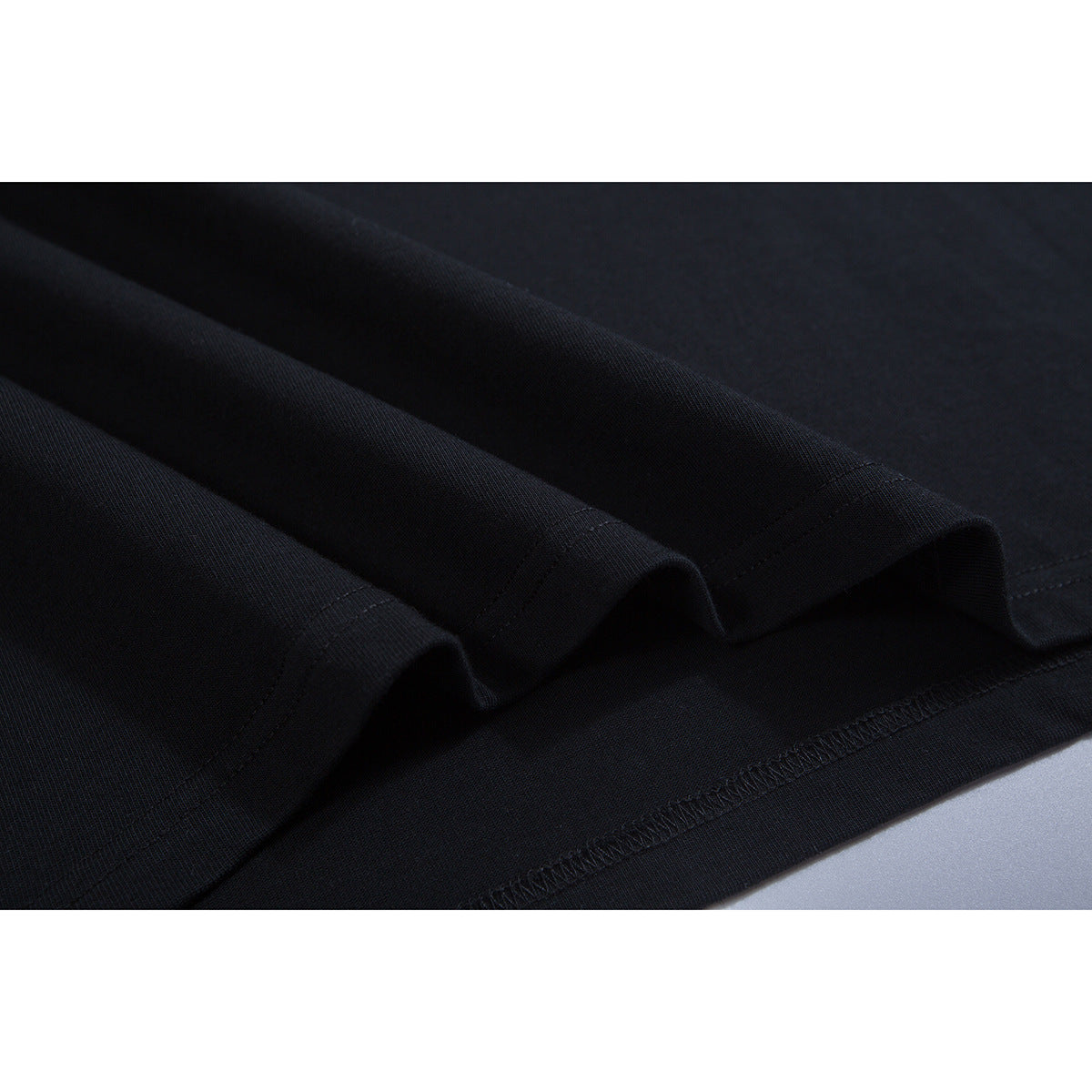 Close-up of black T-shirt fabric folds and double-stitched hem.
