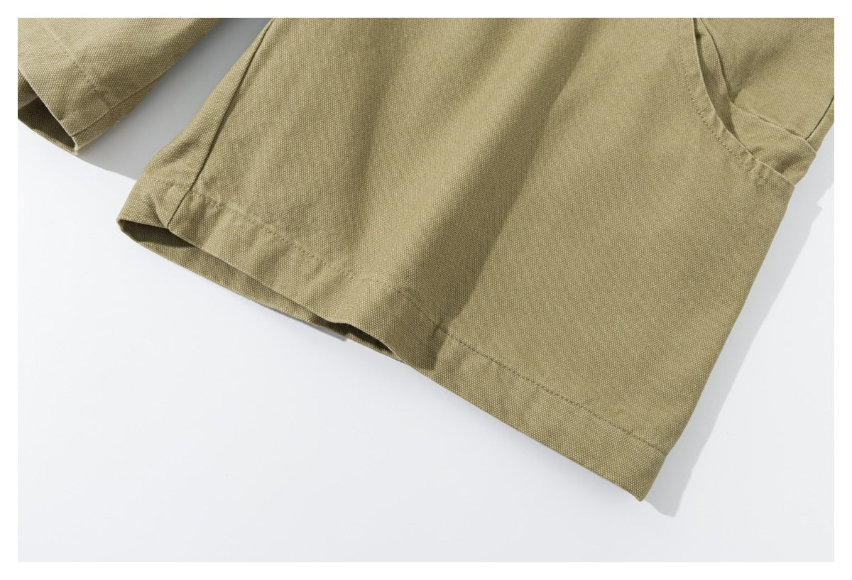 Close-up of a stitched hem and pocket opening on the olive-khaki shorts.
