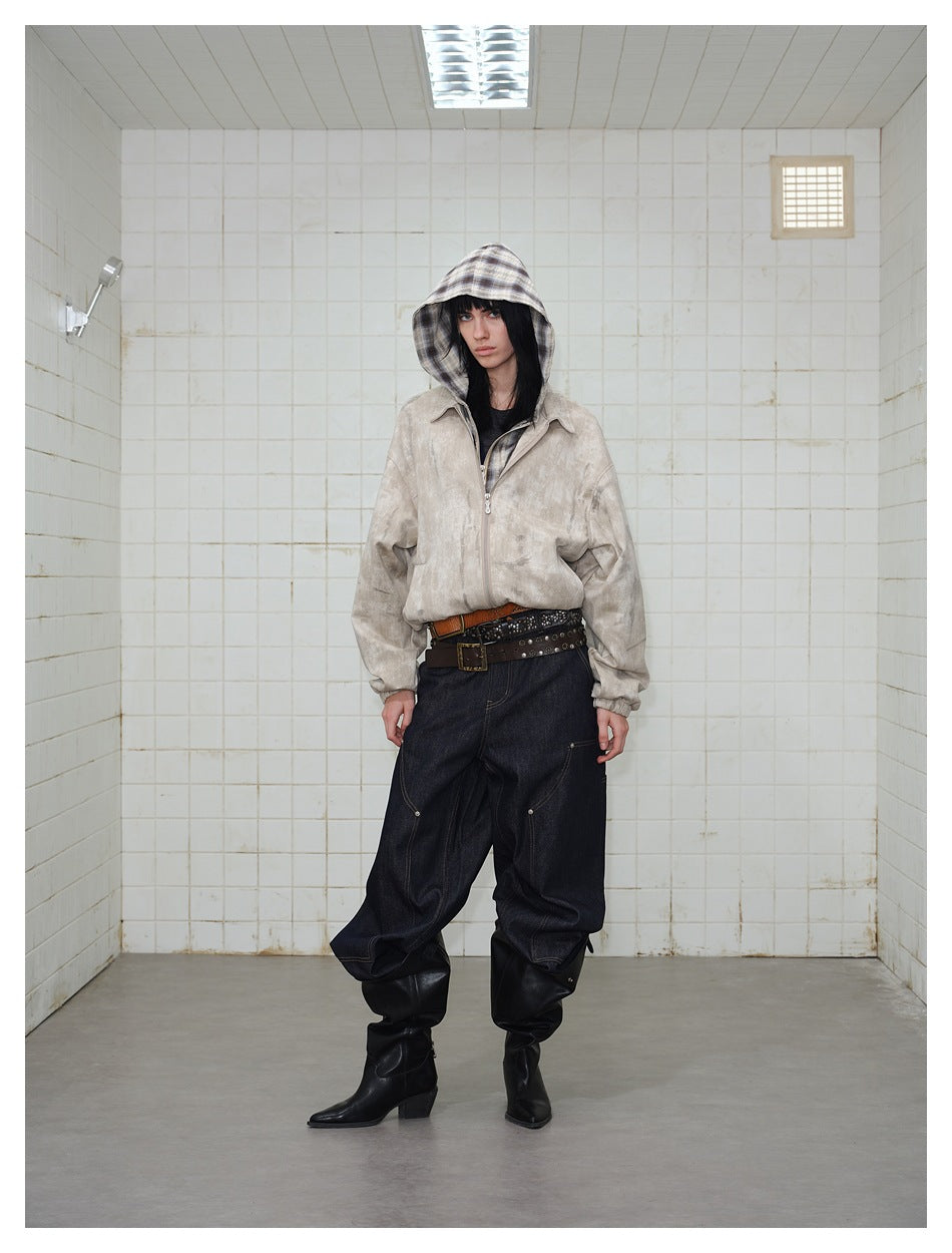 Model wearing a light beige mottled zip jacket with a plaid hood, dark baggy jeans and black boots.