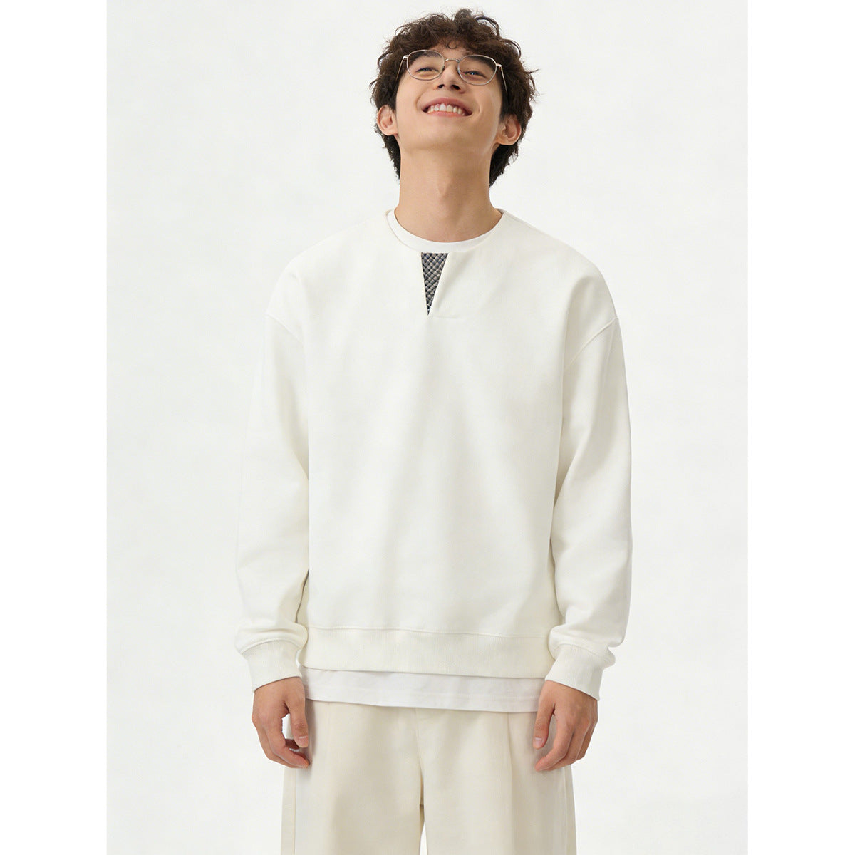 Front view of a model wearing an ivory sweatshirt with a small patterned neckline insert and matching pants.