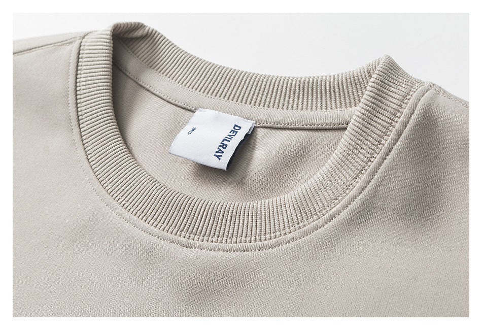Close-up of the ribbed crew neckline and sewn label on a light beige T-shirt.
