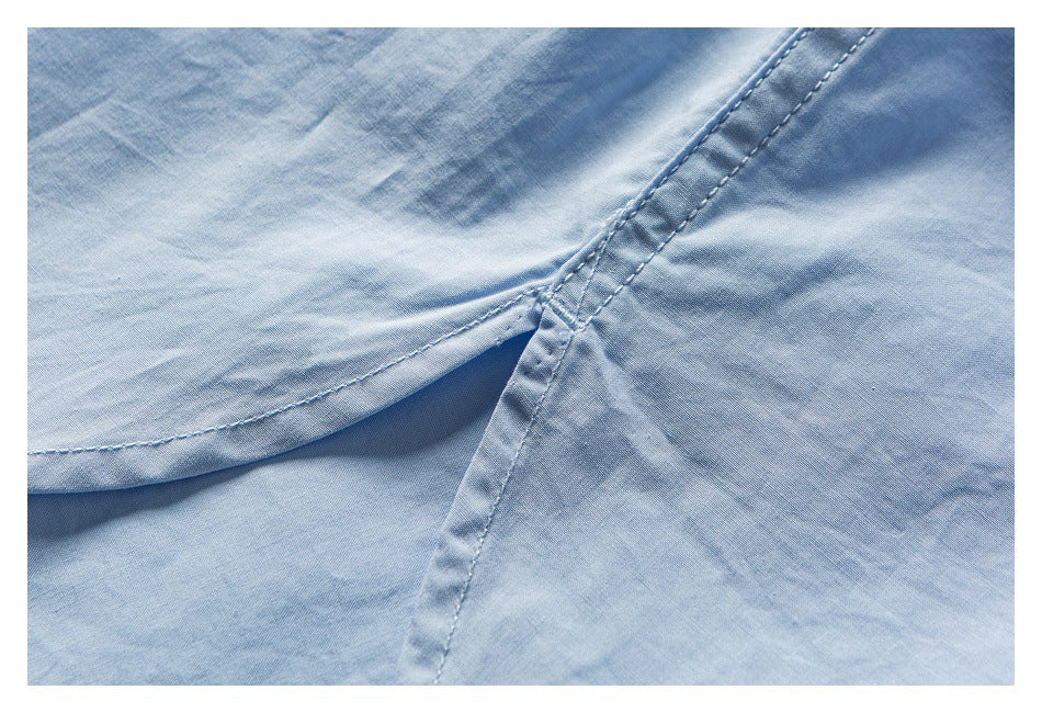 Close-up of light blue garment fabric with a curved stitched seam and intersecting reinforced stitching.