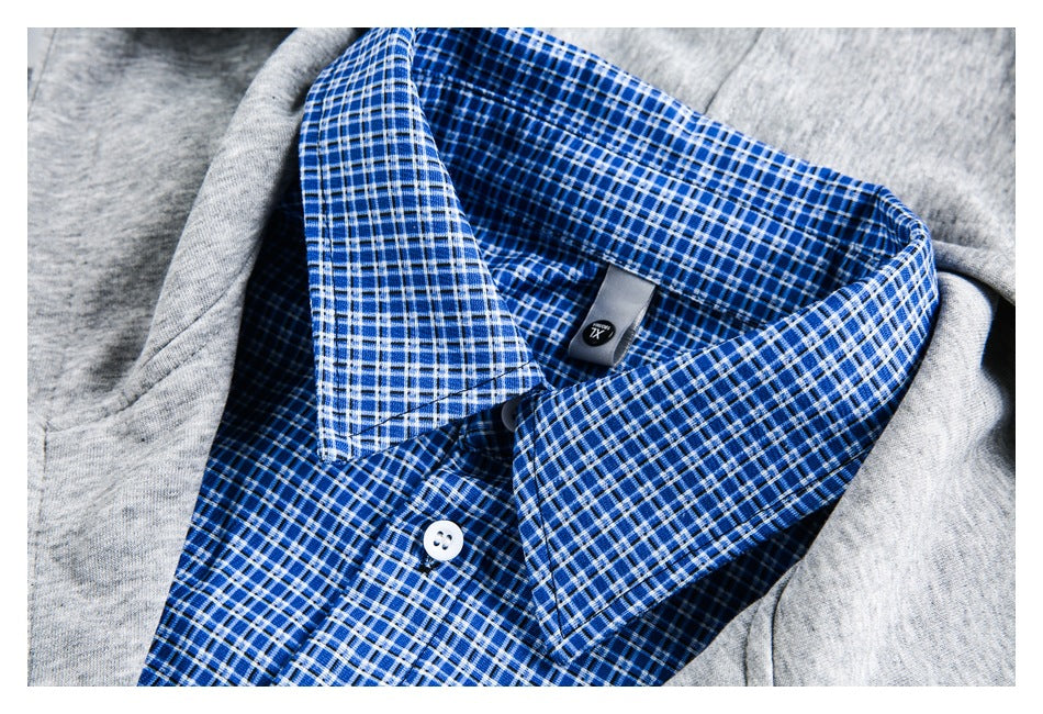Close-up of a blue-and-white plaid shirt collar and button beneath gray garment fabric.