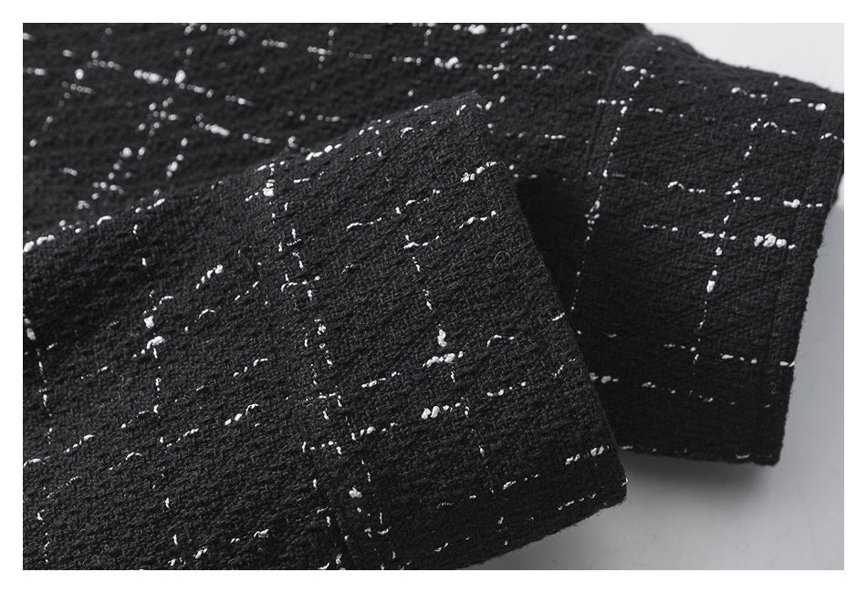 Close-up of black textured fabric with scattered white flecks, folded over itself.