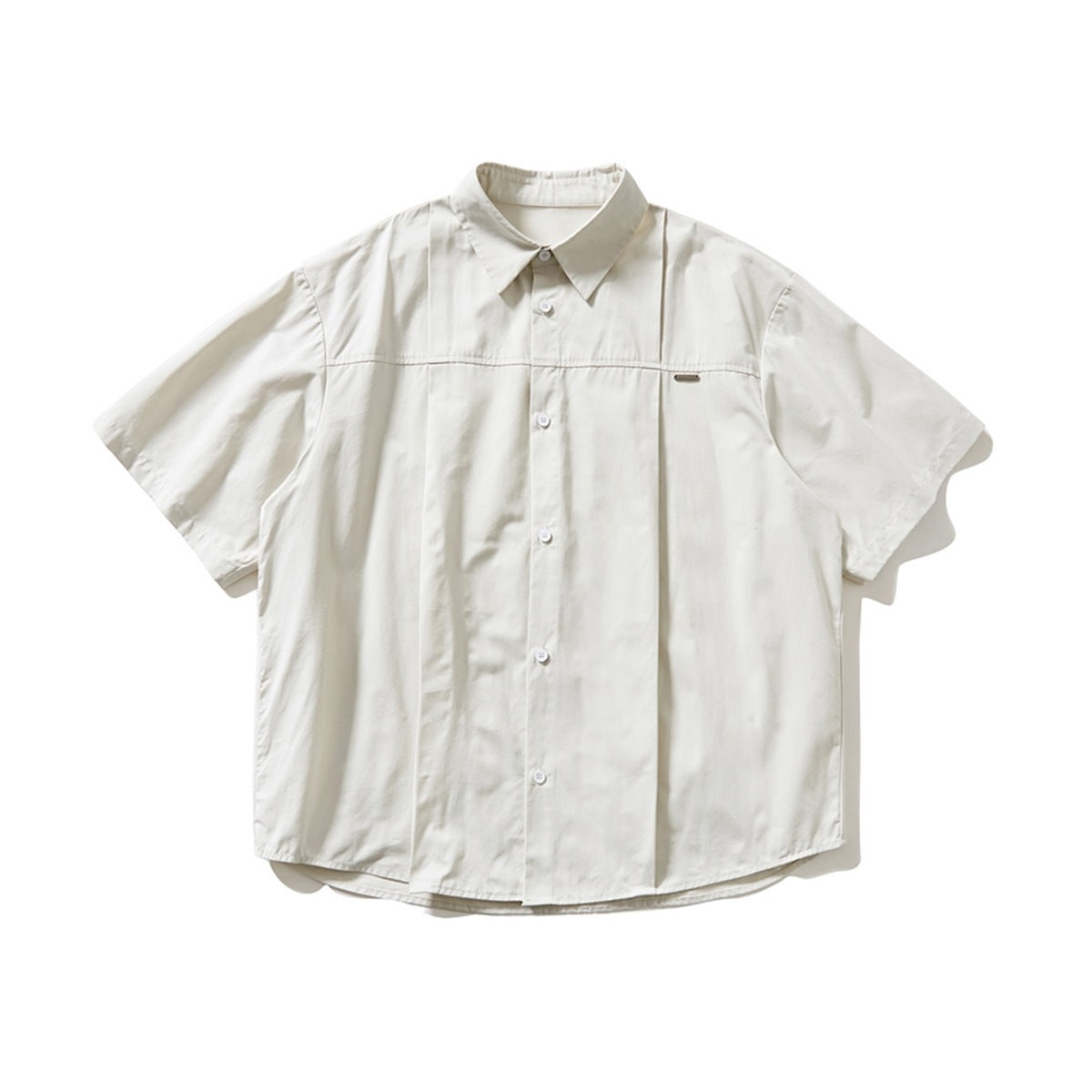 Off-white short-sleeve button-up shirt with pleated front panel, chest seam and small metal tag, flat lay front view