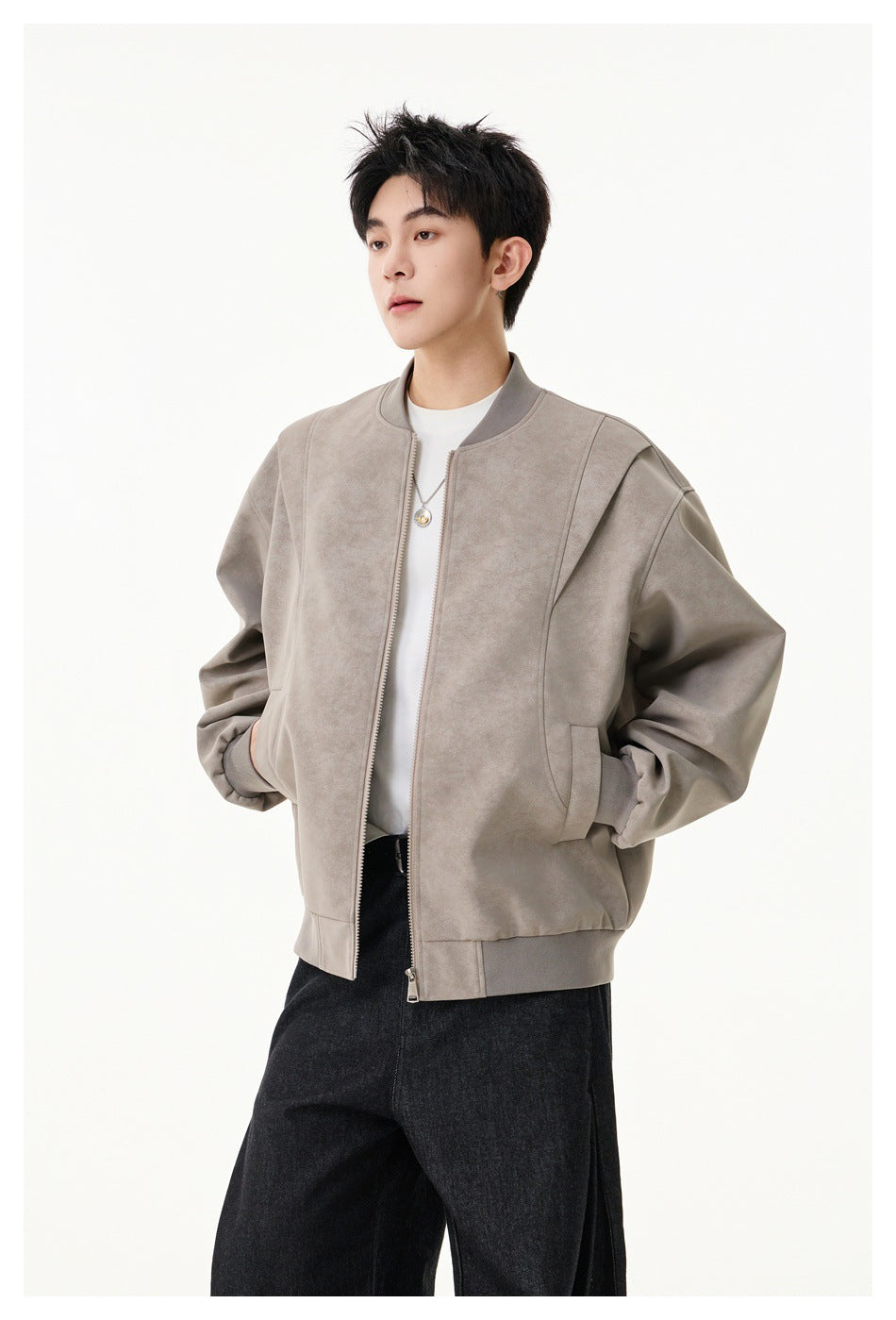 Model wearing an open taupe bomber jacket with a stand collar, zip front, ribbed trim, and black trousers.