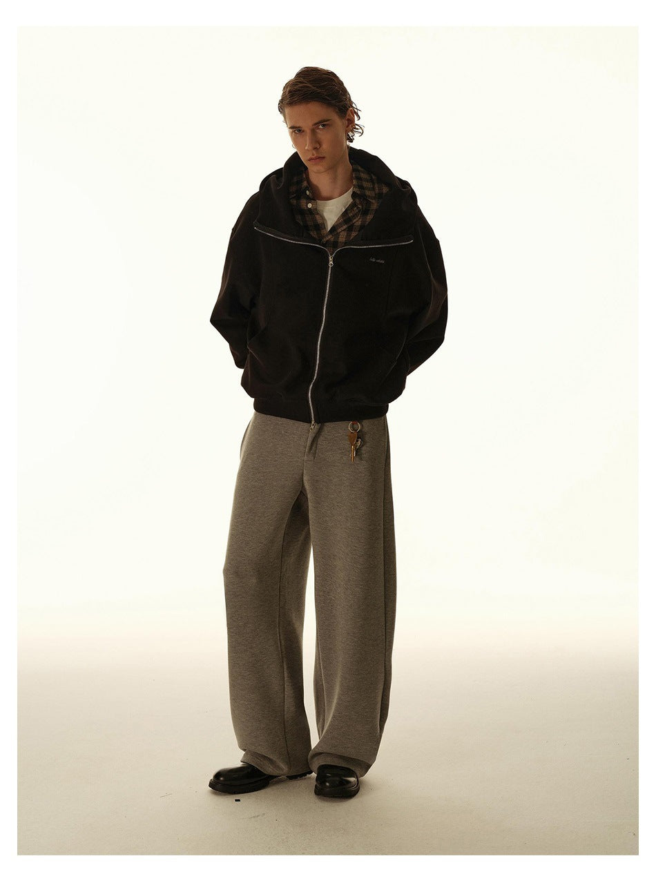 Full-length model wearing a black zip-up hoodie over a plaid shirt with wide-leg gray pants.