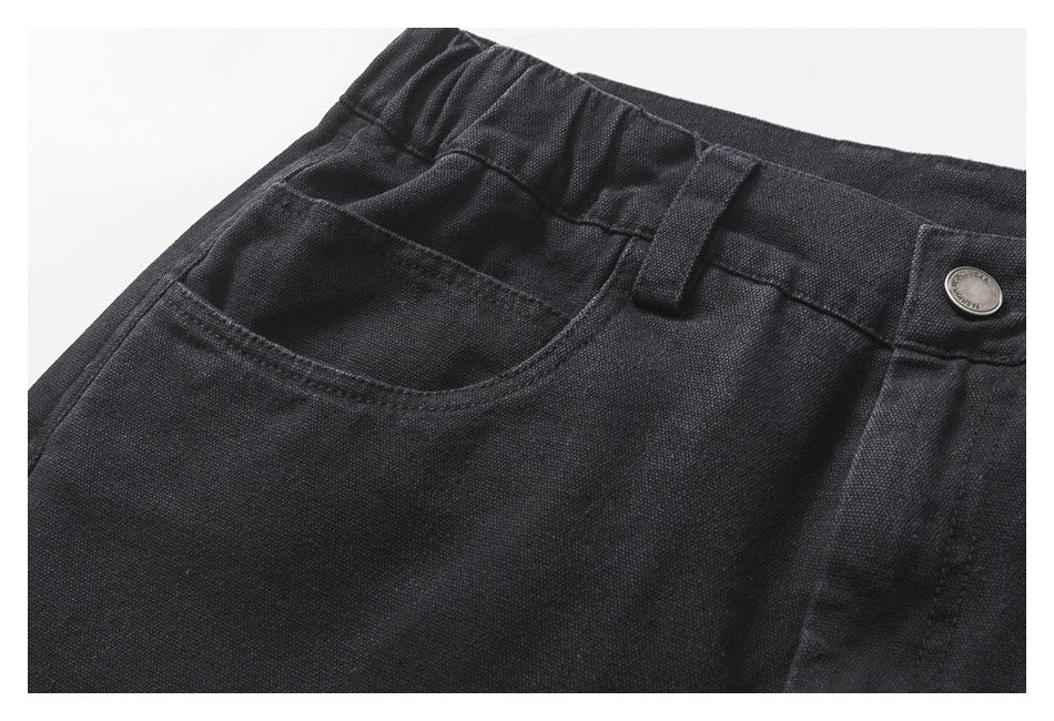 Close-up of a charcoal shorts front pocket, elasticated waistband, belt loop and metal button.