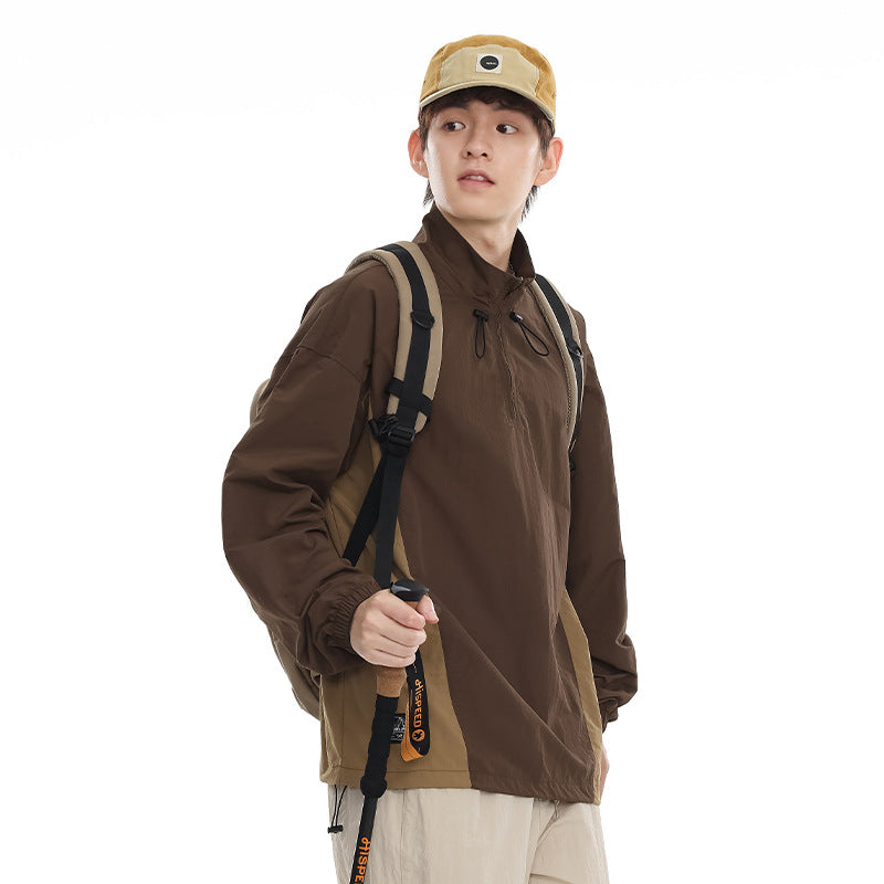 Model wearing a brown high-neck pullover with drawcords and beige side panels, paired with a tan cap and backpack.