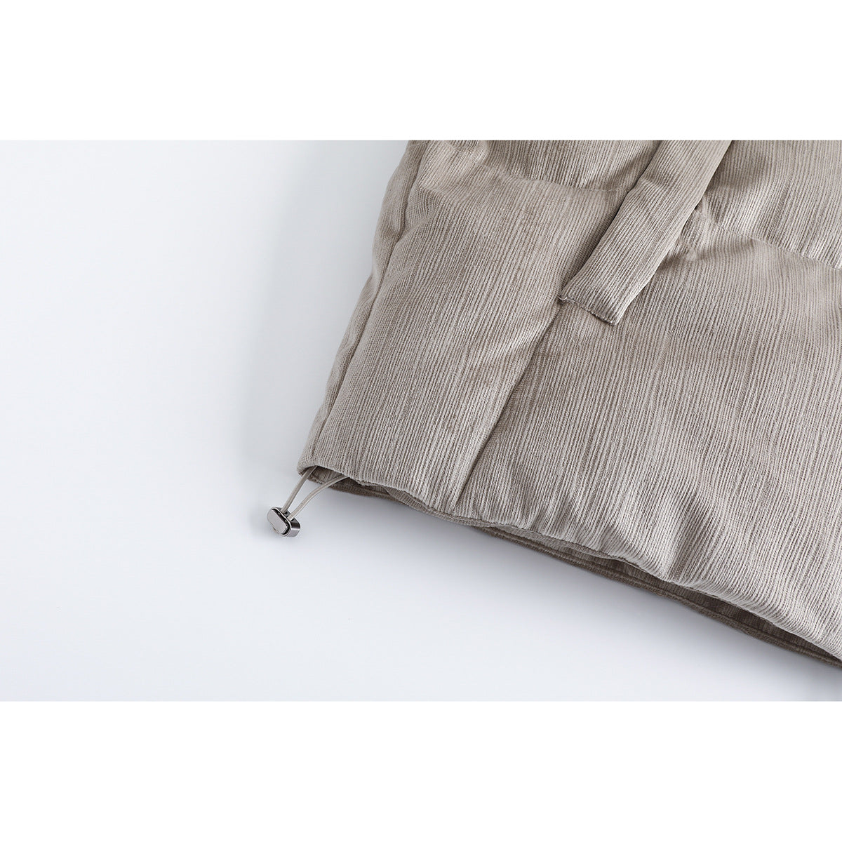 Close-up of the light taupe jacket's hem and adjustable drawcord toggle.