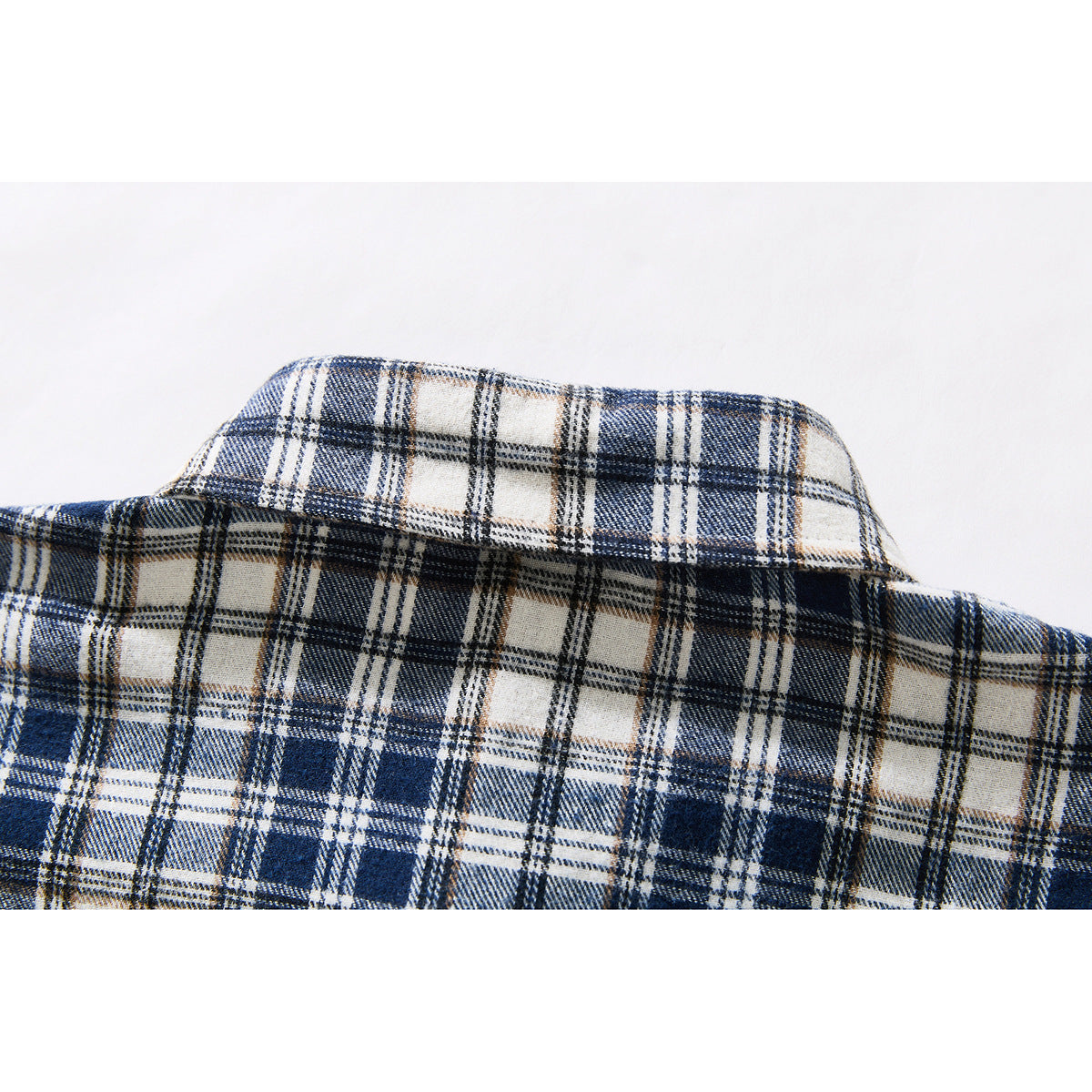 Close-up of the pointed collar and shoulder seam on a navy and cream plaid shirt.
