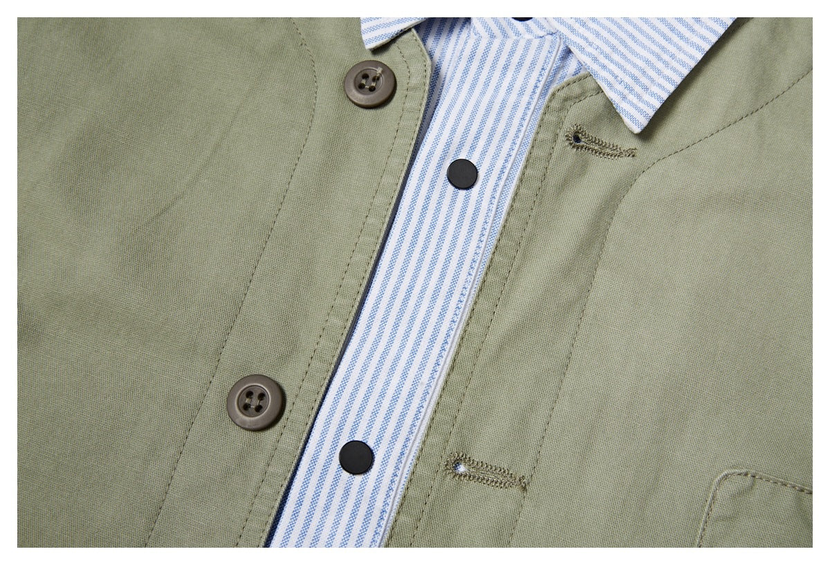 Close-up of an olive-green shirt front with a blue-and-white striped placket, dark snaps, buttons, and stitched buttonholes.