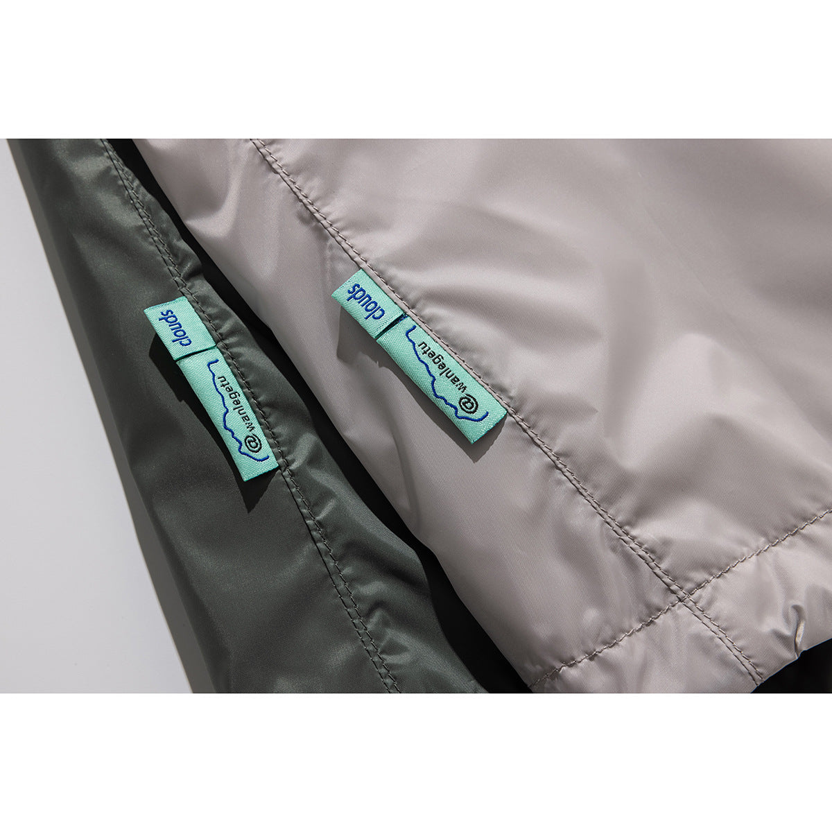 Close-up of sewn turquoise labels on light taupe and dark olive jacket fabric.