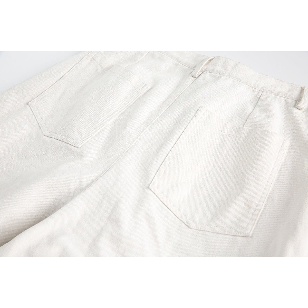 Close-up of the two rear patch pockets and belt loops on white shorts.