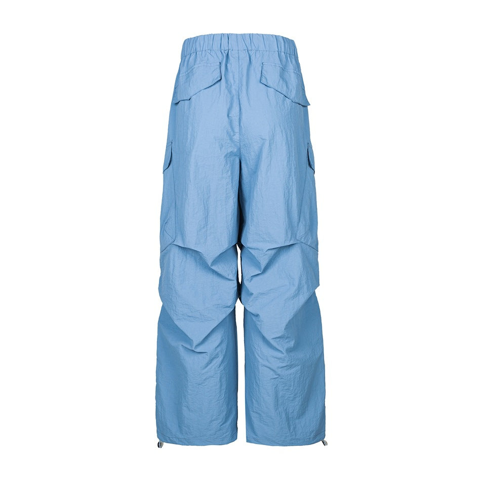 Blue wide-leg cargo pants back view with elastic waist, flap back pockets, side cargo pockets and drawcord hems
