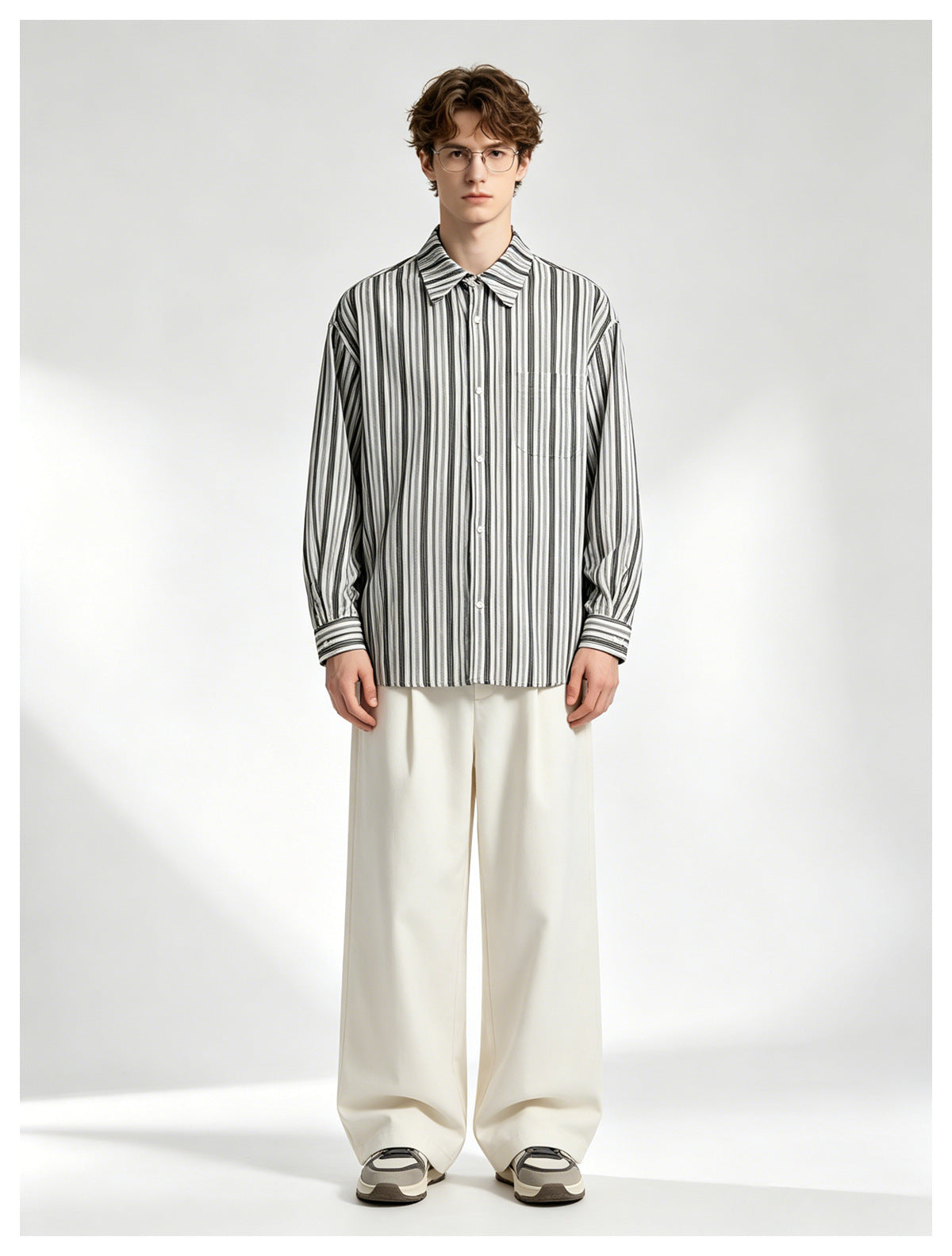 Model wearing a black-and-white vertically striped button-up shirt with wide-leg cream trousers.
