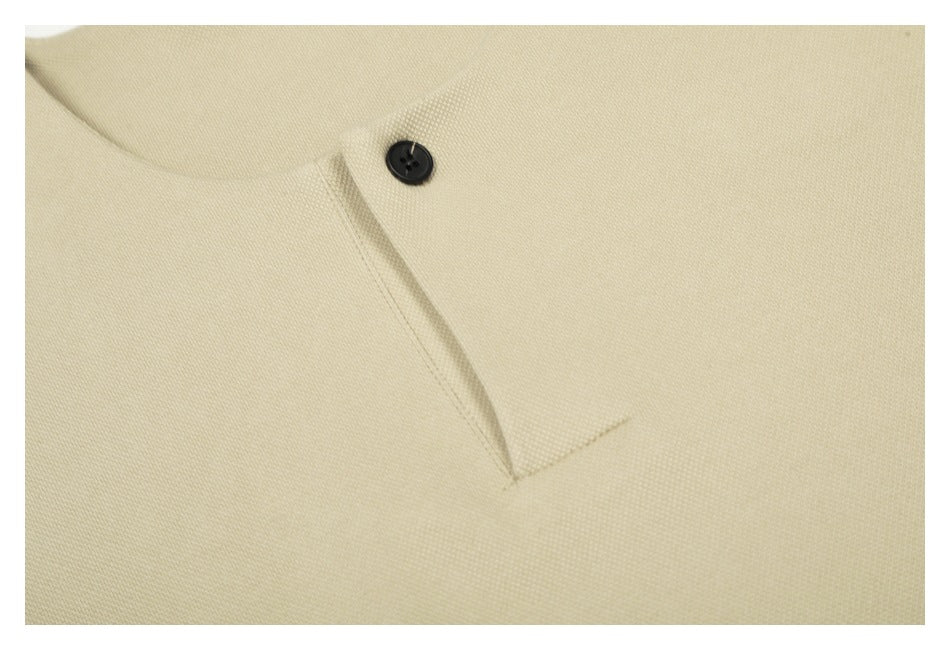 Close-up of the cream top's single black button and stitched short placket.