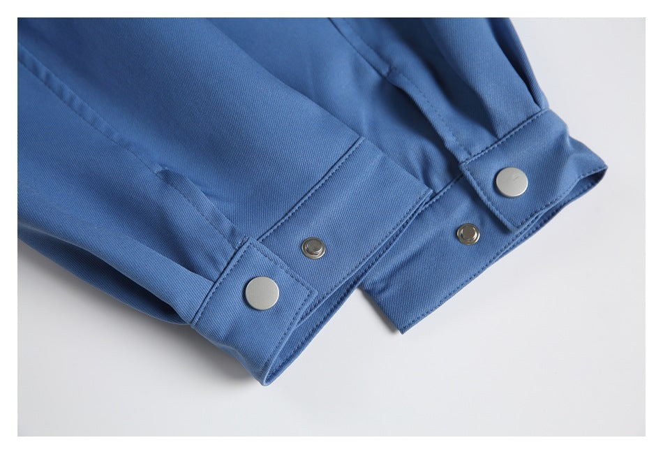 Close-up of blue garment cuffs with silver snap buttons and stitched seams on a white background.