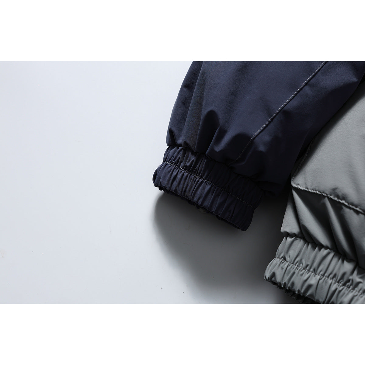Close-up of the jacket's navy sleeve and gathered elastic cuff beside the gray body.