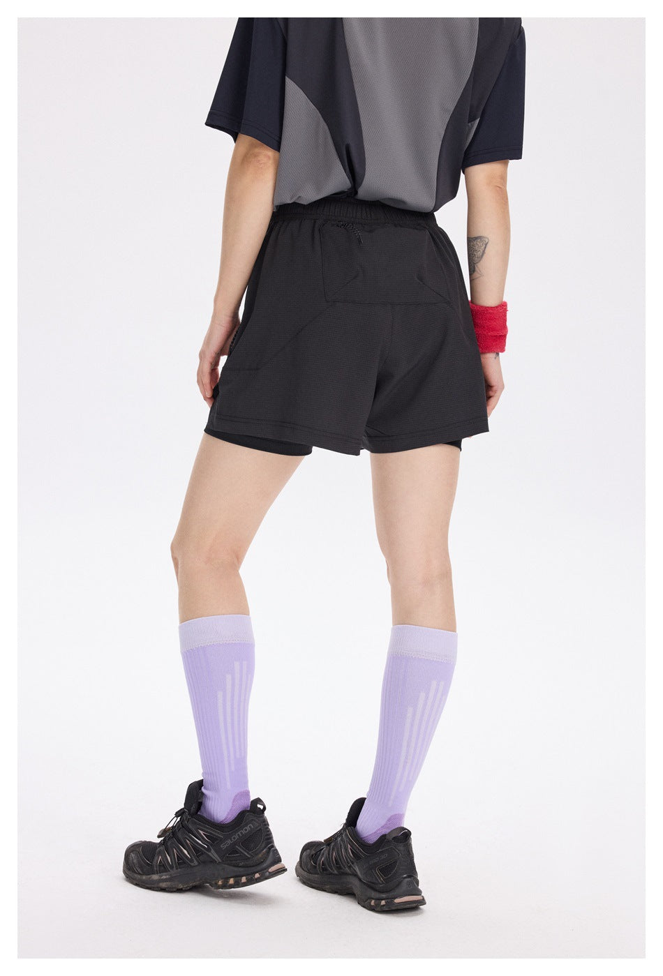 Rear view of a model wearing black running shorts with an elastic waist and back pocket.