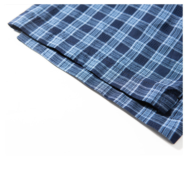 Close-up of the layered hem and stitching on a navy blue plaid shirt.