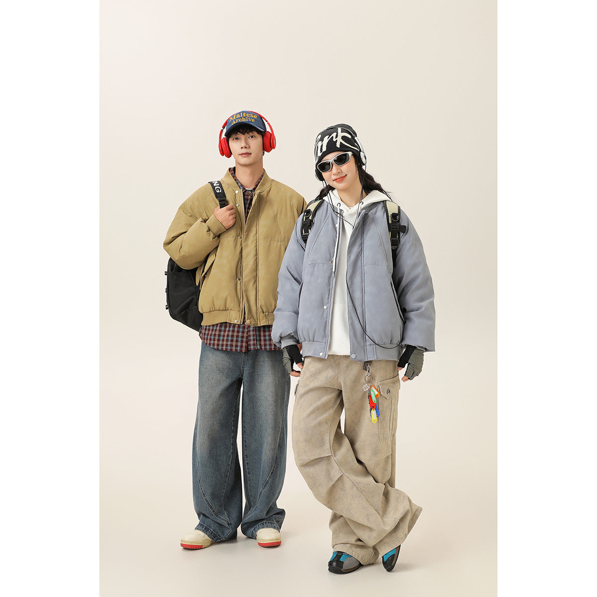 Two models wear oversized bomber jackets: one tan and one blue-gray, styled with loose trousers and casual accessories.