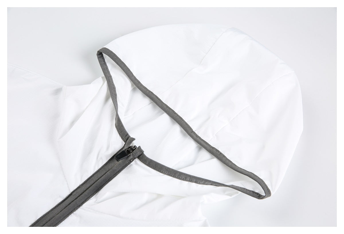 Close-up of a white garment with dark gray piping and a small zipper at the edge.