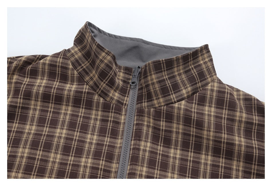 Close-up of a brown plaid jacket's stand collar, gray lining, and front zipper.