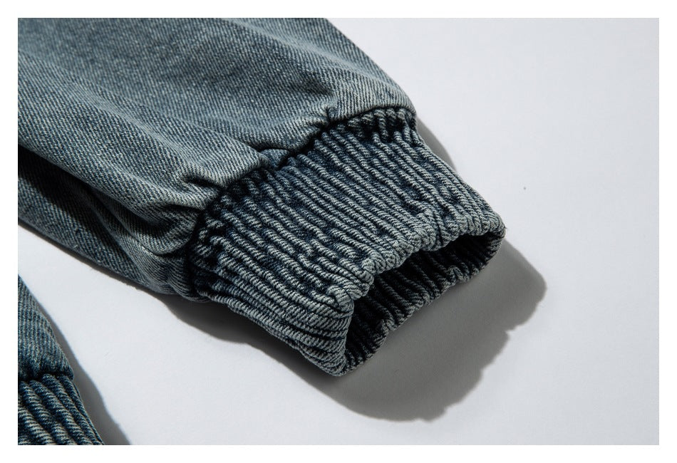 Close-up of a gathered blue-gray denim sleeve ending in a wide ribbed cuff.
