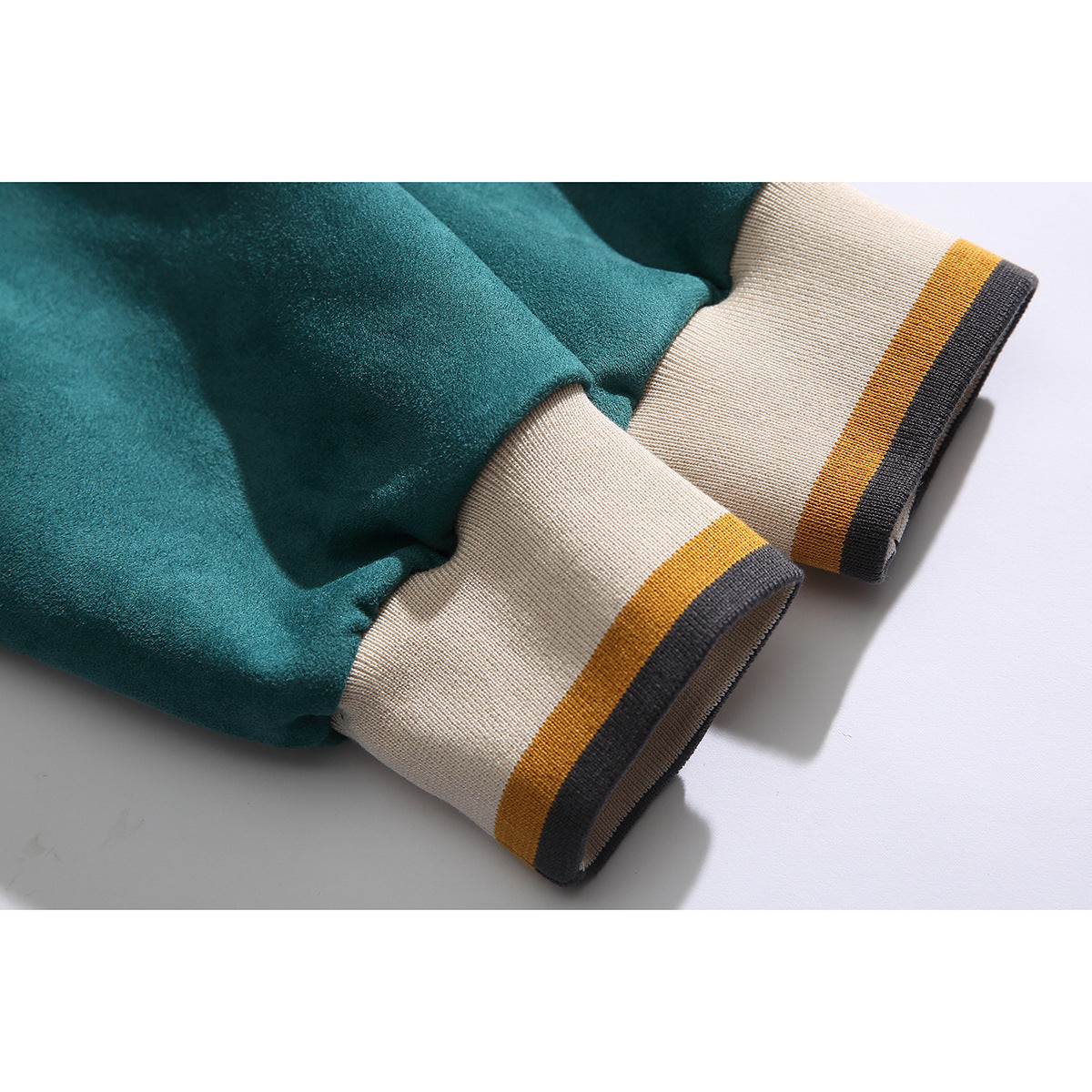 Close-up of teal sweatshirt sleeves and wide cream cuffs with mustard and charcoal stripes.