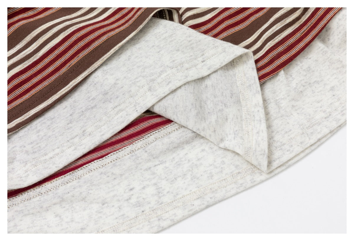 Close-up of the inside hem and stitching of a brown, burgundy, and cream striped top with a light gray underside.