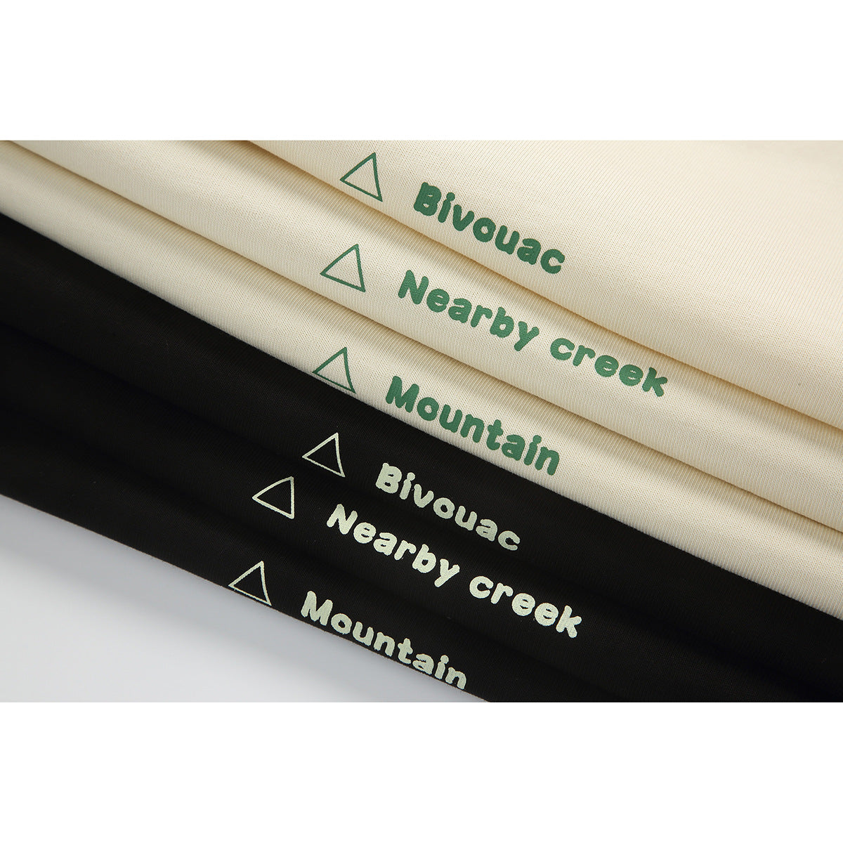Folded cream and black fabric shows repeated green or cream triangle icons and the words “Bivouac,” “Nearby creek,” and