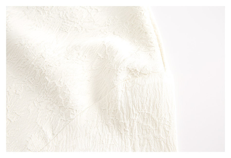 Close-up of ivory fabric with raised floral texture and a curved seam.