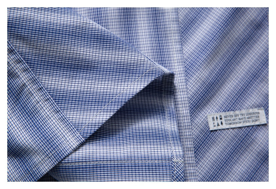 Close-up of the checked shirt's folded fabric and seams beside its small sewn English-text label.