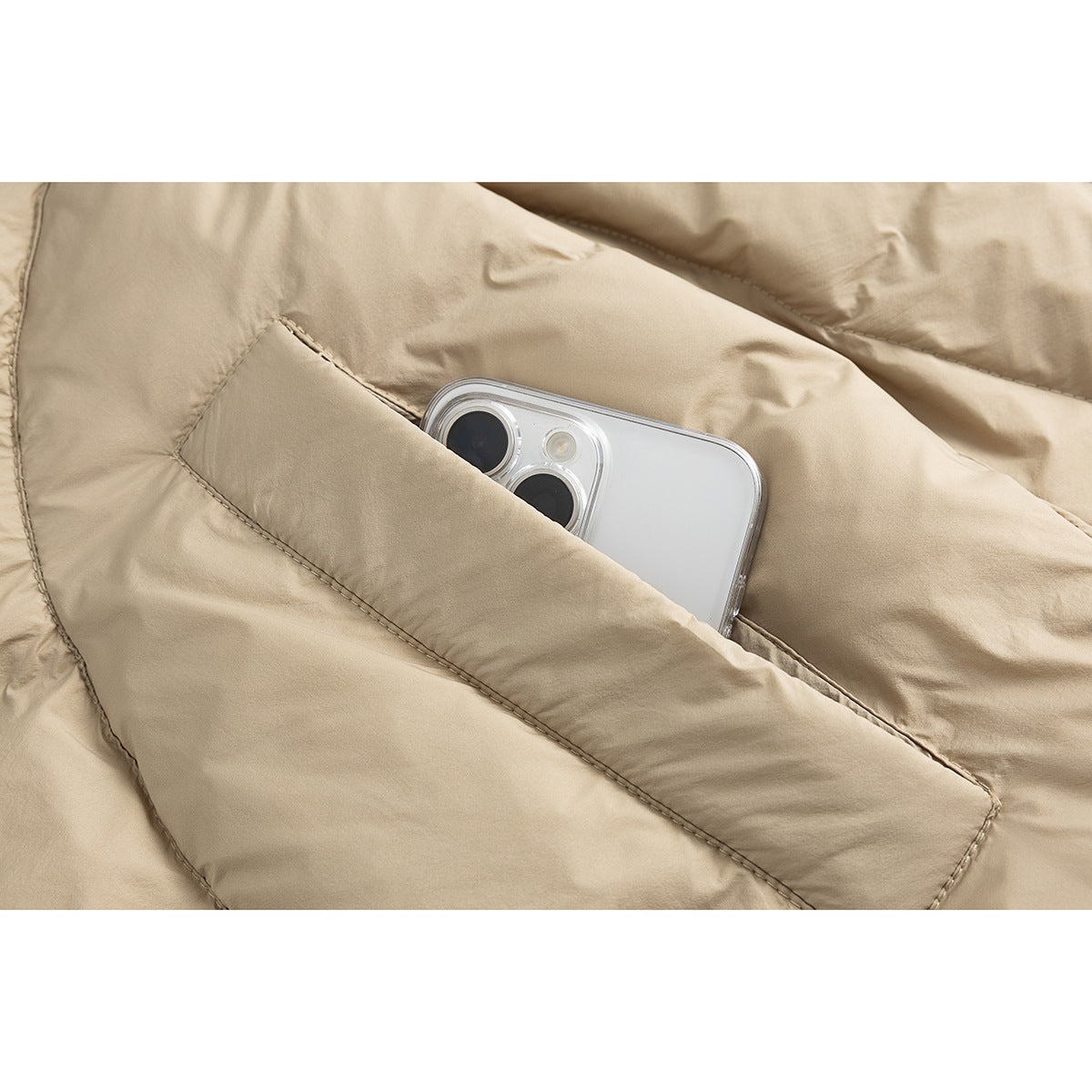 Close-up of a beige padded jacket's stitched pocket holding a smartphone.
