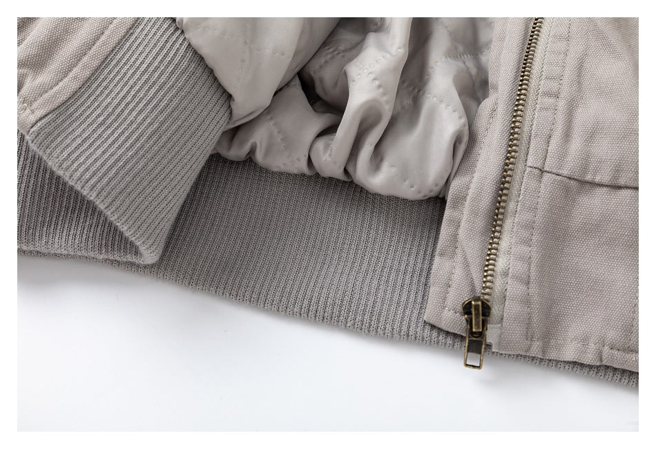 Close-up of a light taupe jacket's ribbed knit hem, lining, and zipper.