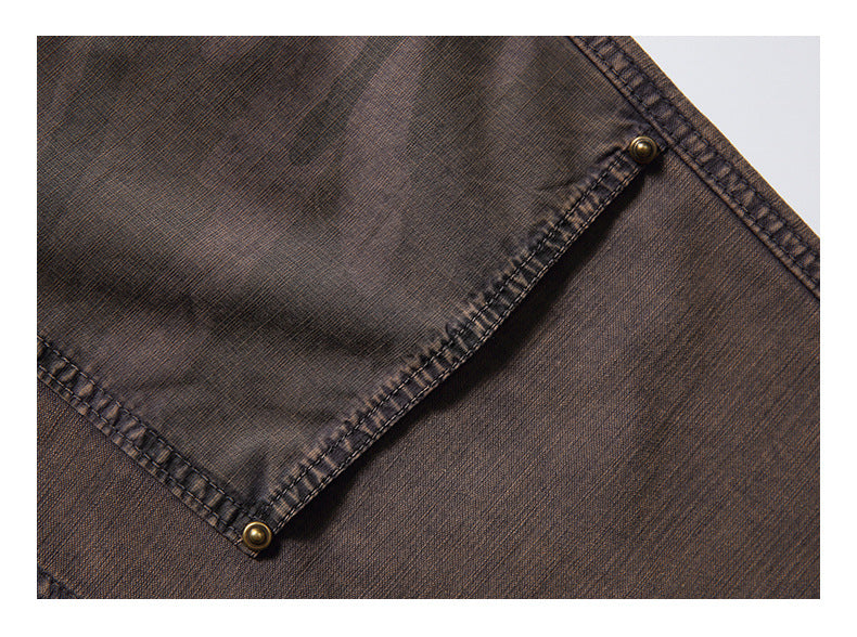 Close-up of a brown garment pocket flap with stitched edges and brass-tone snap fasteners.