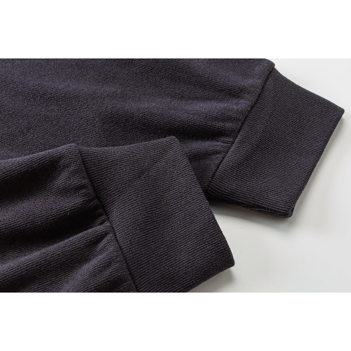 Close-up of the ribbed cuff and sleeve seam on a dark charcoal long-sleeve top.