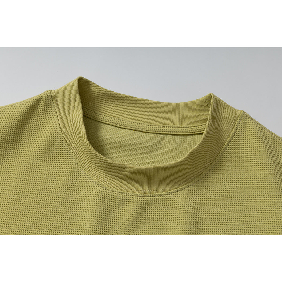 Close-up of a muted olive-yellow textured T-shirt neckline with a ribbed crew collar.