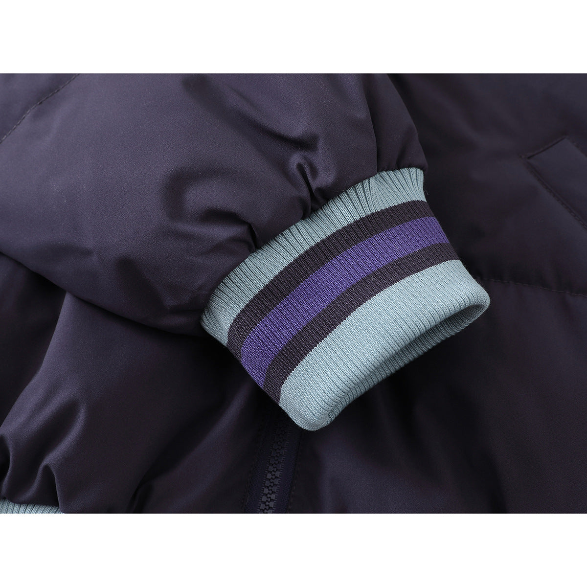 Close-up of a dark purple jacket sleeve ending in a light blue ribbed cuff with purple and dark stripes.