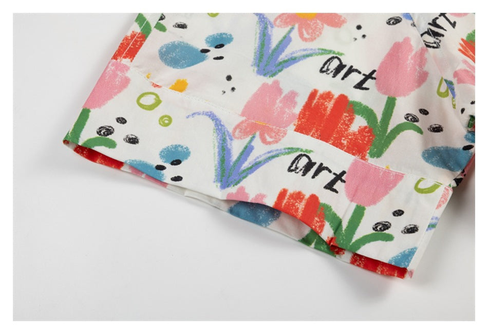 Close-up of a white garment hem with colorful flower and doodle print and black lettering.