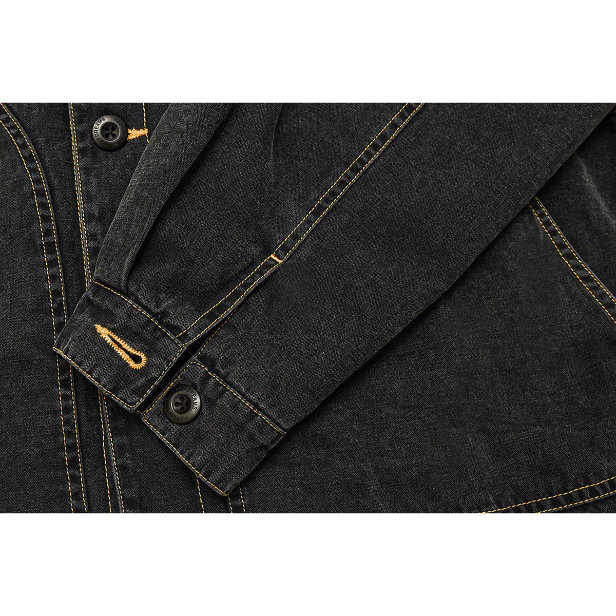 Close-up of a charcoal denim jacket sleeve cuff with a button and yellow embroidered buttonhole.