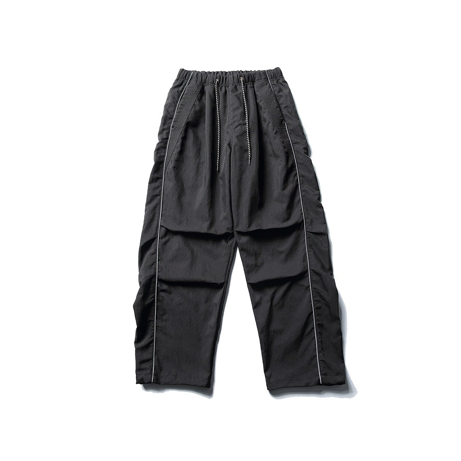 Black wide-leg drawstring pants with light side piping and knee pleats, flat lay front view