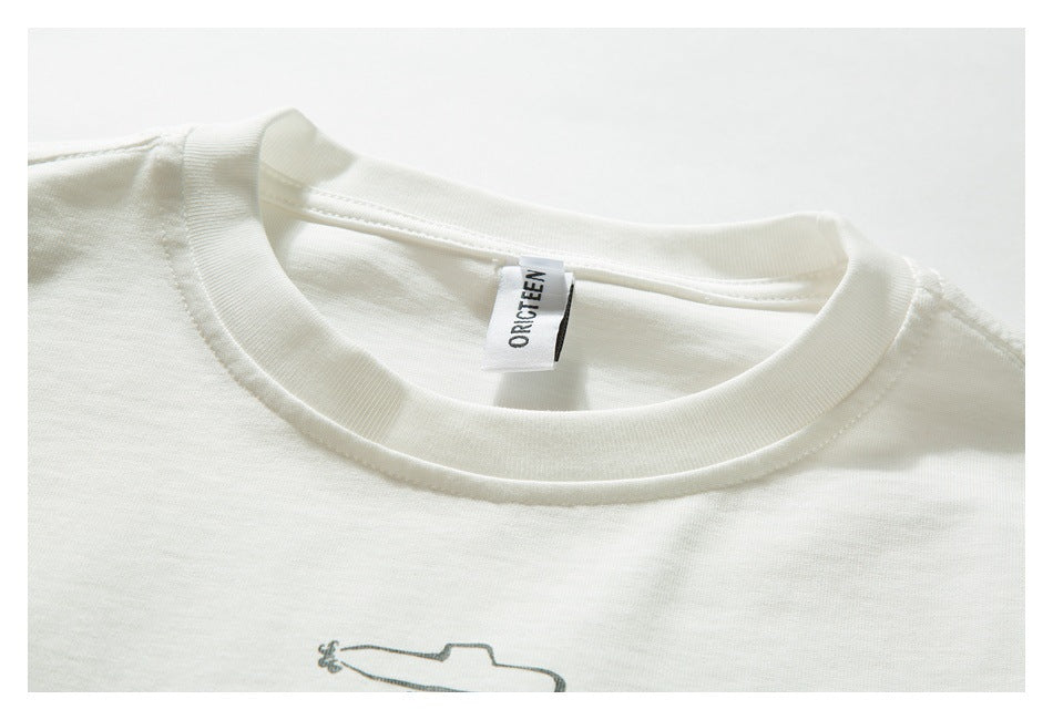 Close-up of an ivory T-shirt’s ribbed crew neck, sewn-in label, and partial small chest graphic.