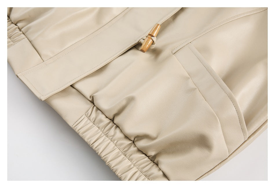 Close-up of beige trousers showing a gathered waistband, stitched pocket, and tan drawstring ends.