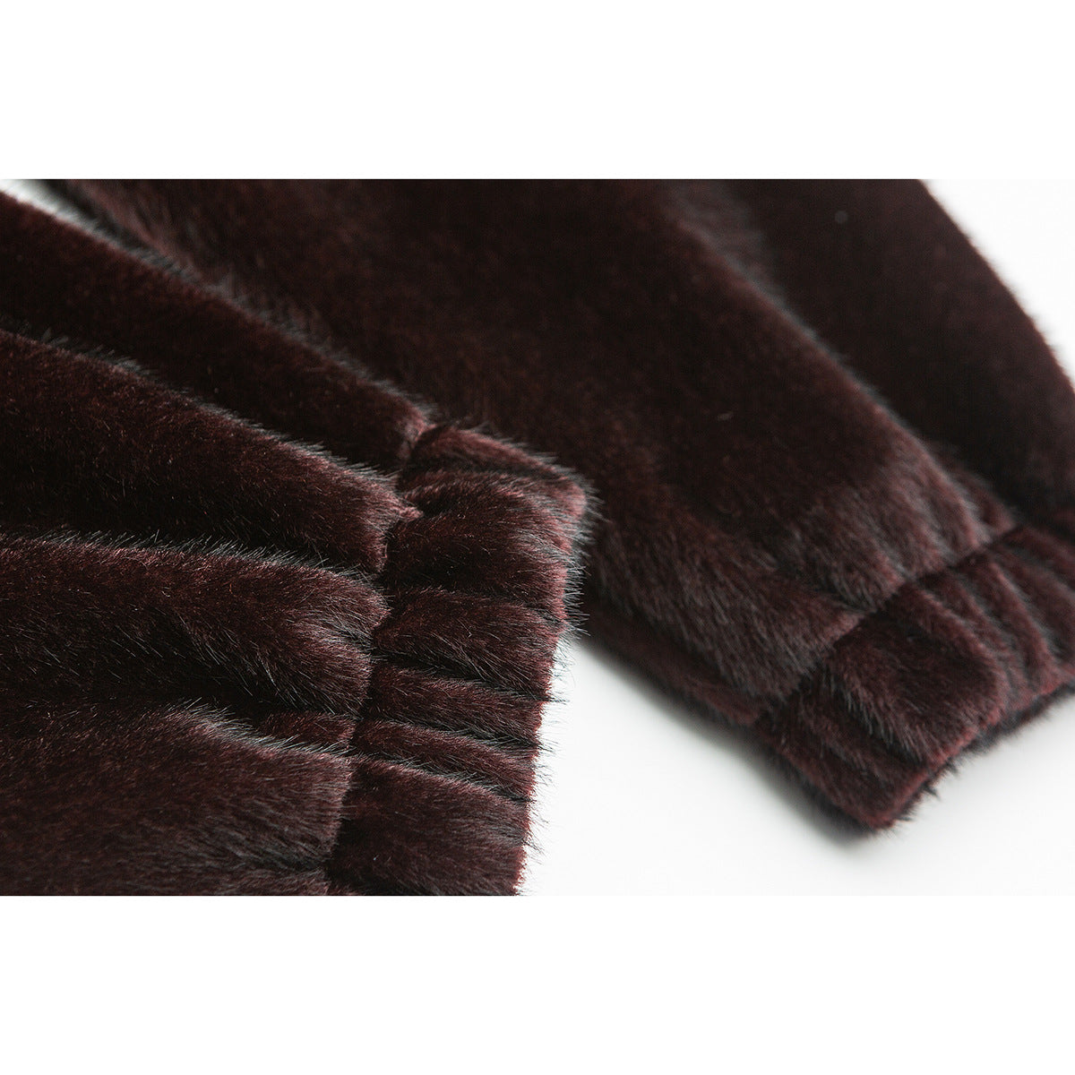Close-up of the plush sleeve and gathered cuff of a dark burgundy-brown jacket.